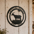 Custom goat farm metal sign in satin black finish mounted on a whitewashed barn wall with a personalized farm name, goat silhouette, and established year.