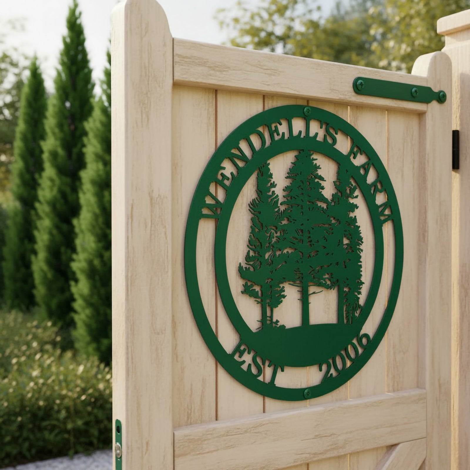 A forest green circular metal sign customized for "Wendell's Farm Est. 2006" with carved evergreen trees, attached to a light-colored wooden garden gate.