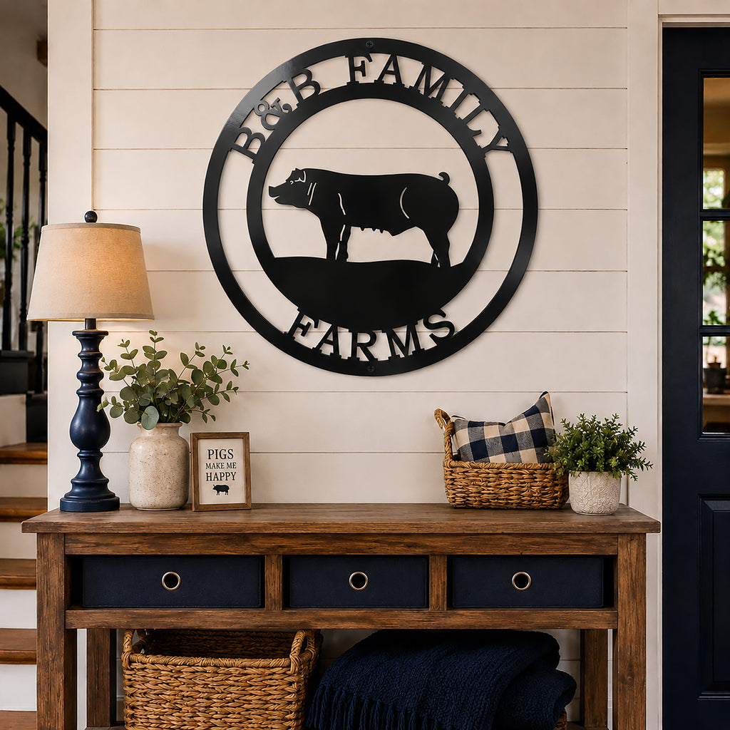 Large matte black round metal monogram sign featuring a pig and family farm text hanging on a living room wall above a wooden entryway console table.