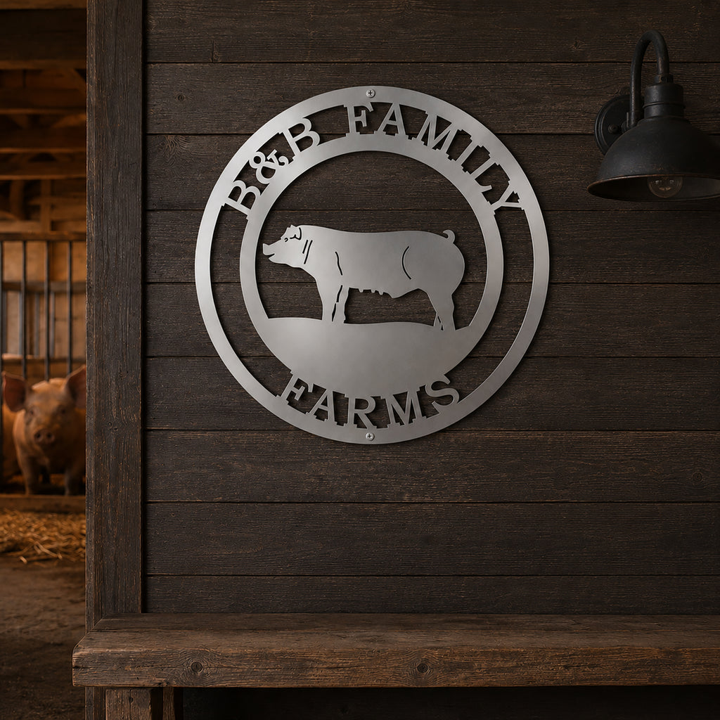 Personalized B&B Family Farms round metal sign in a brushed silver steel finish hanging on a dark rustic wooden wall inside a barn next to a vintage light fixture.