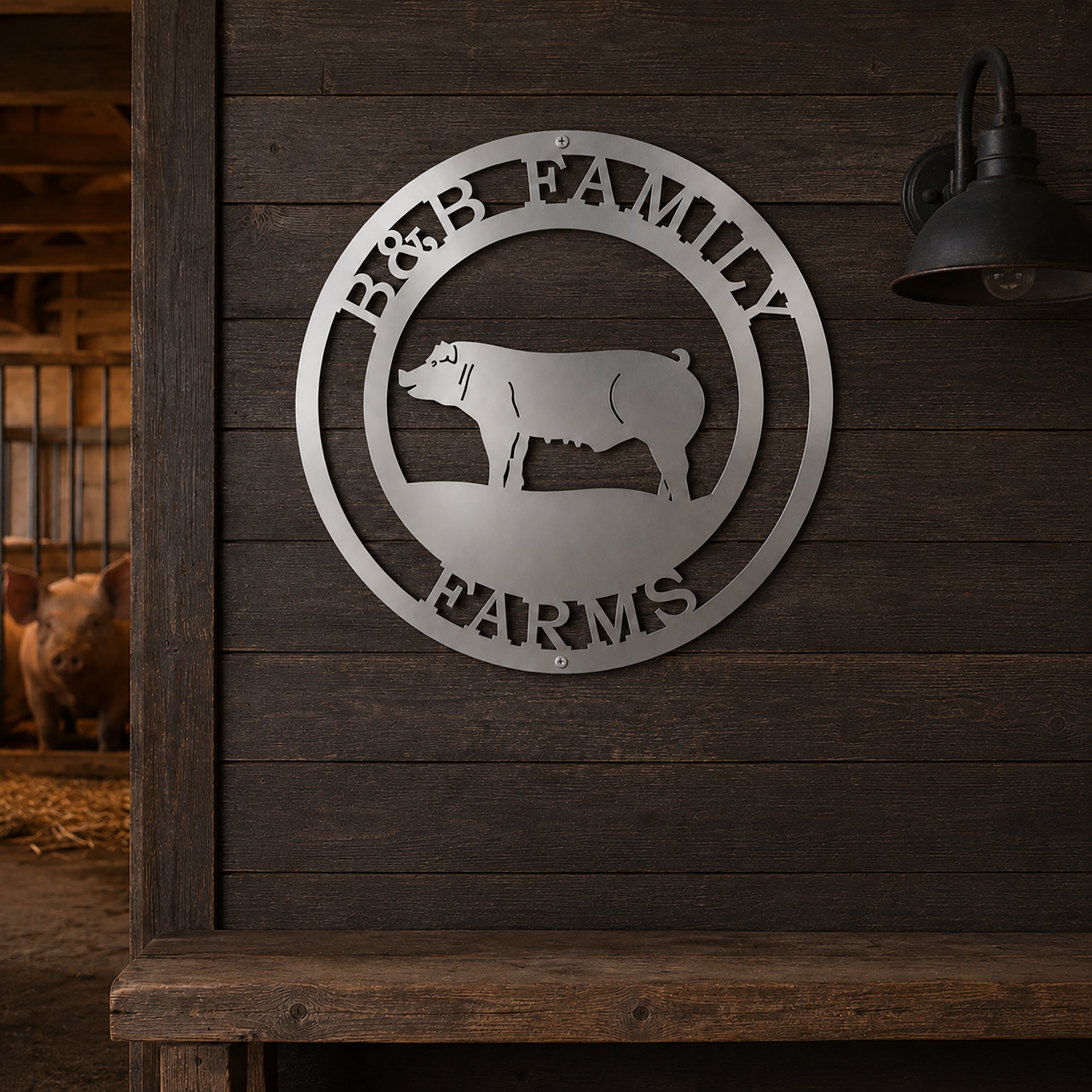 Personalized B&B Family Farms round metal sign in a brushed silver steel finish hanging on a dark rustic wooden wall inside a barn next to a vintage light fixture.
