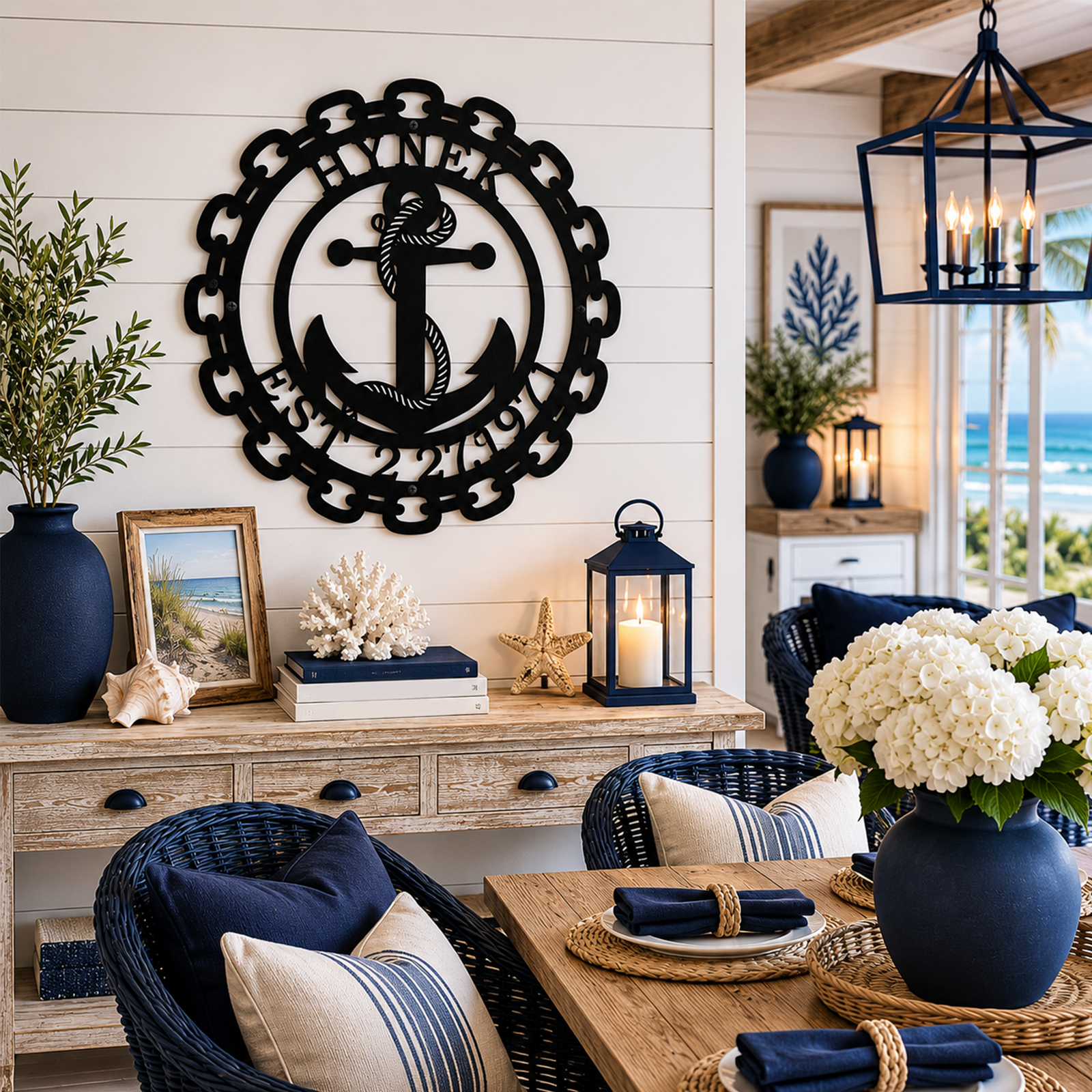 Matte black personalized nautical anchor metal sign with custom name Hynek and established date 2 21 1977 hanging on a white shiplap wall of a luxury covered patio overlooking the ocean.