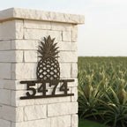 Oil rubbed bronze pineapple house number sign with address 5474 displayed on a white stone entrance pillar