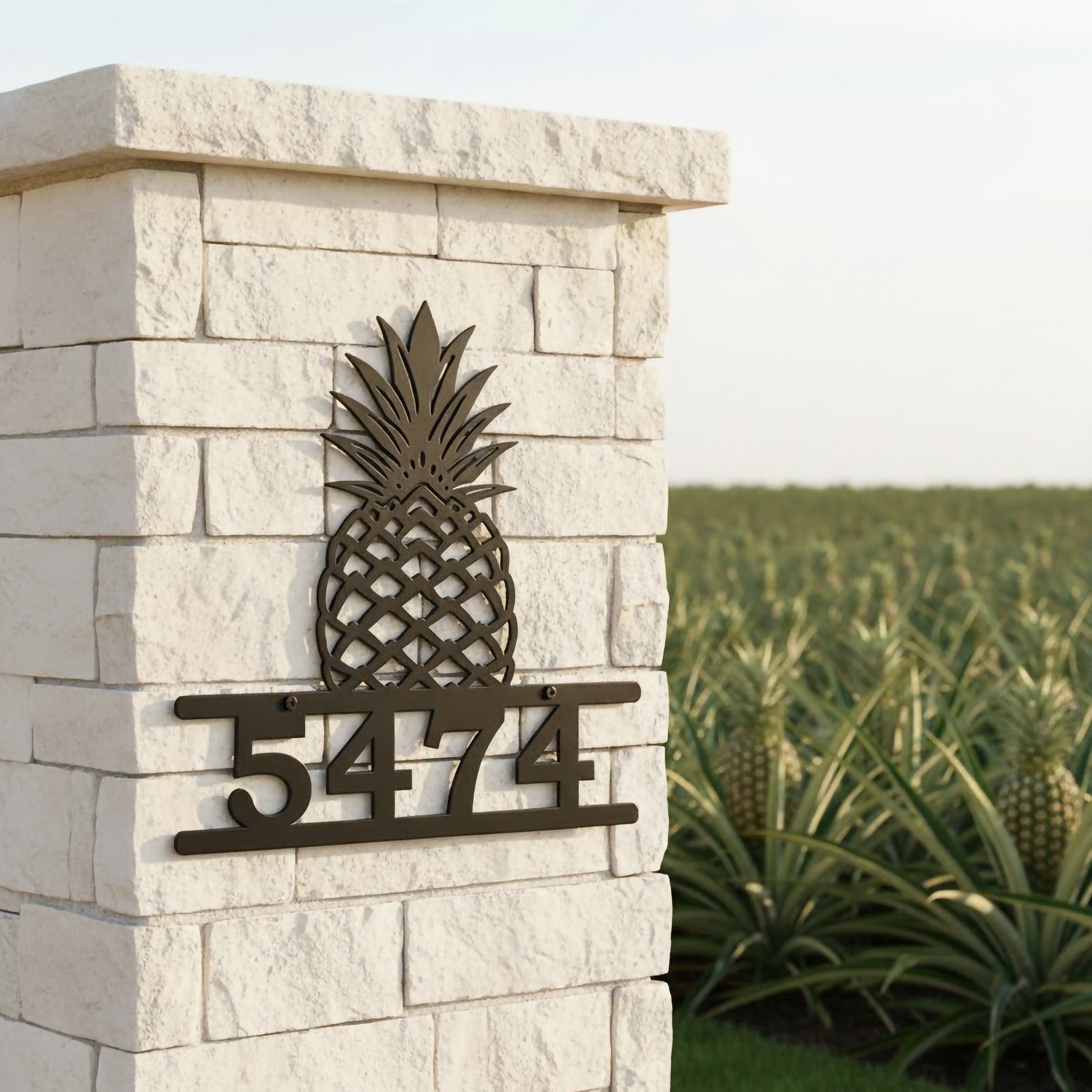 Oil rubbed bronze pineapple house number sign with address 5474 displayed on a white stone entrance pillar