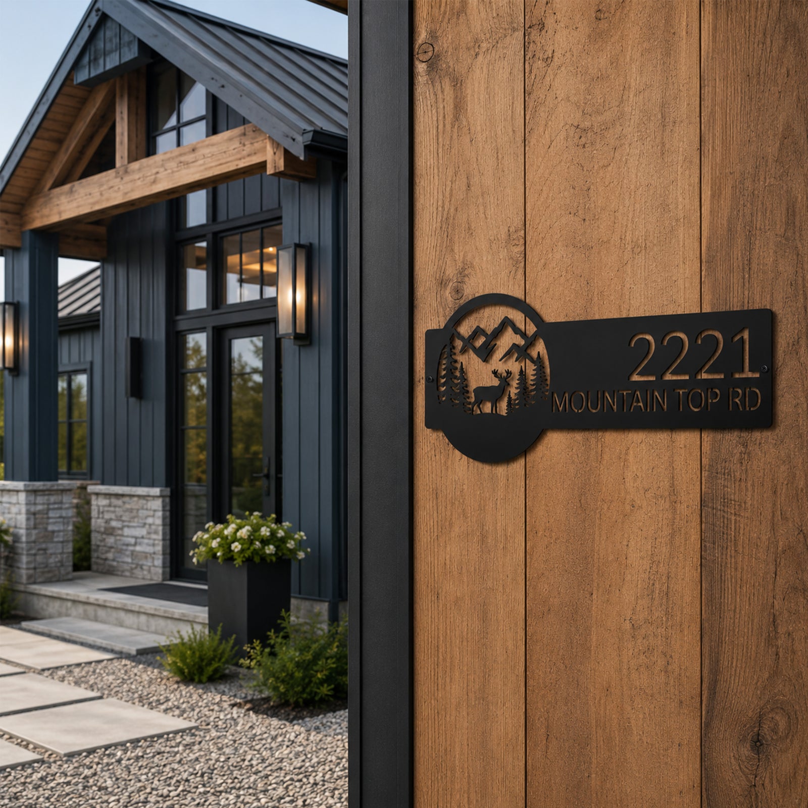 Black custom mountain lodge address sign with elk and pine tree design mounted beside modern cabin entrance