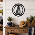 Black pineapple established family metal sign displayed above rustic wood table with pineapples and farmhouse decorations