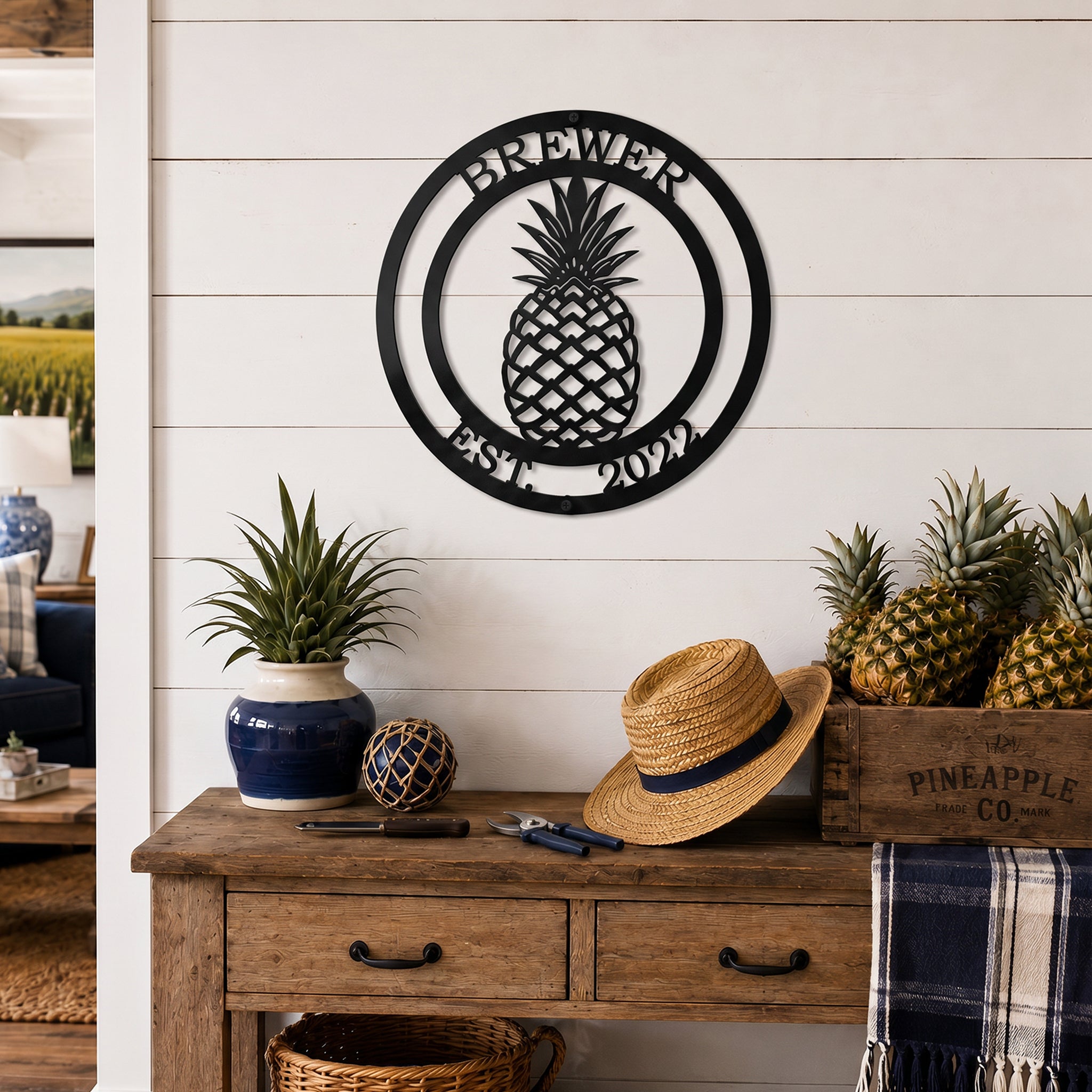 Black pineapple established family metal sign displayed above rustic wood table with pineapples and farmhouse decorations