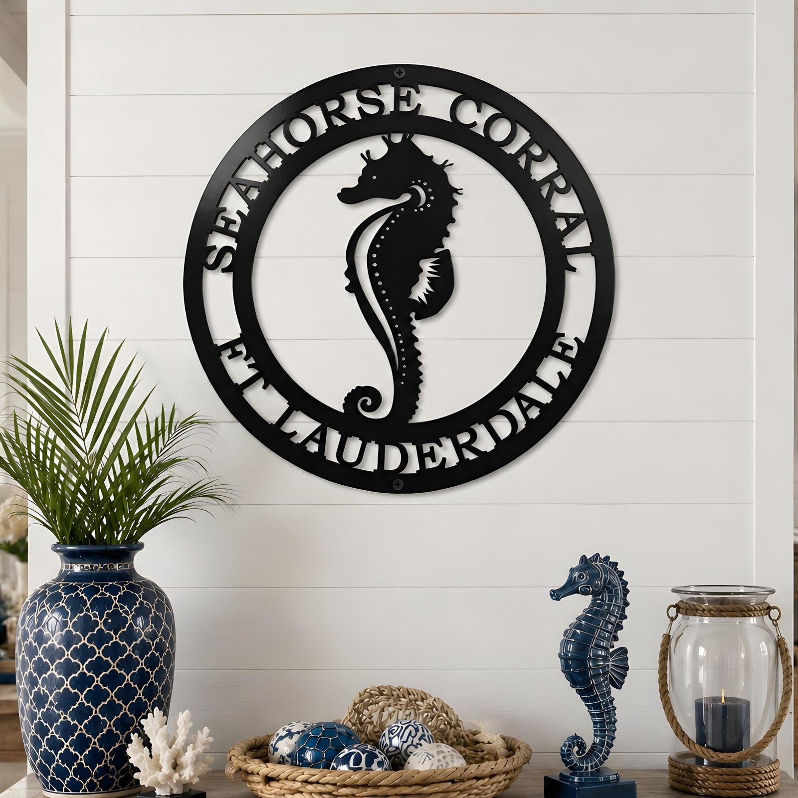 Black seahorse coastal metal wall sign displayed above rustic console table with nautical beach decor accessories