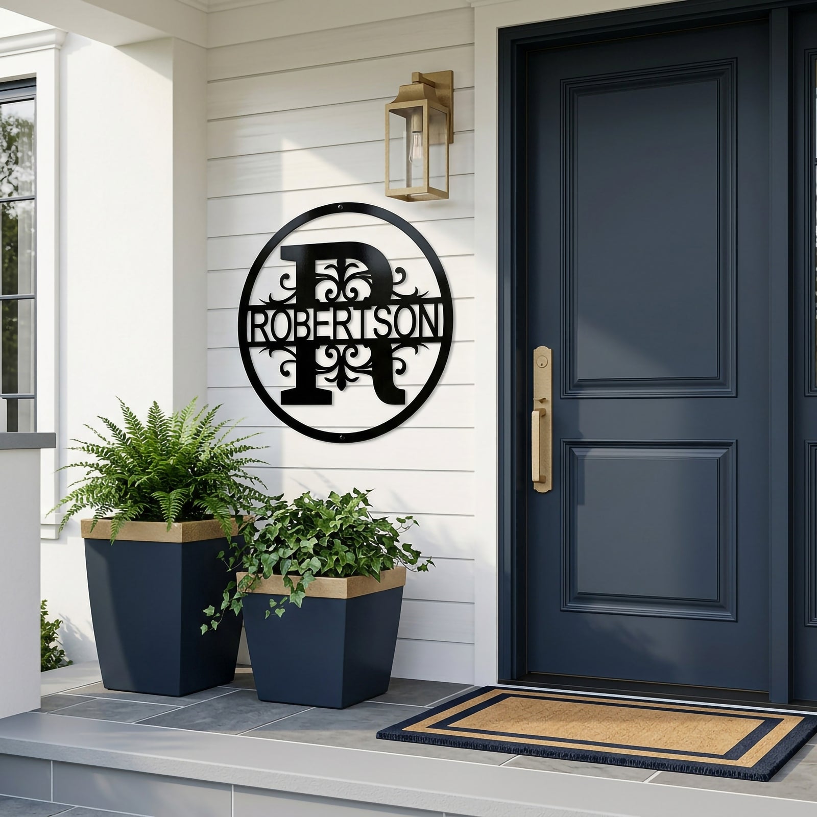 Gloss black personalized family split monogram metal sign with custom text Robertson mounted on a white shiplap exterior wall next to a dark navy blue front door and potted fern plants.