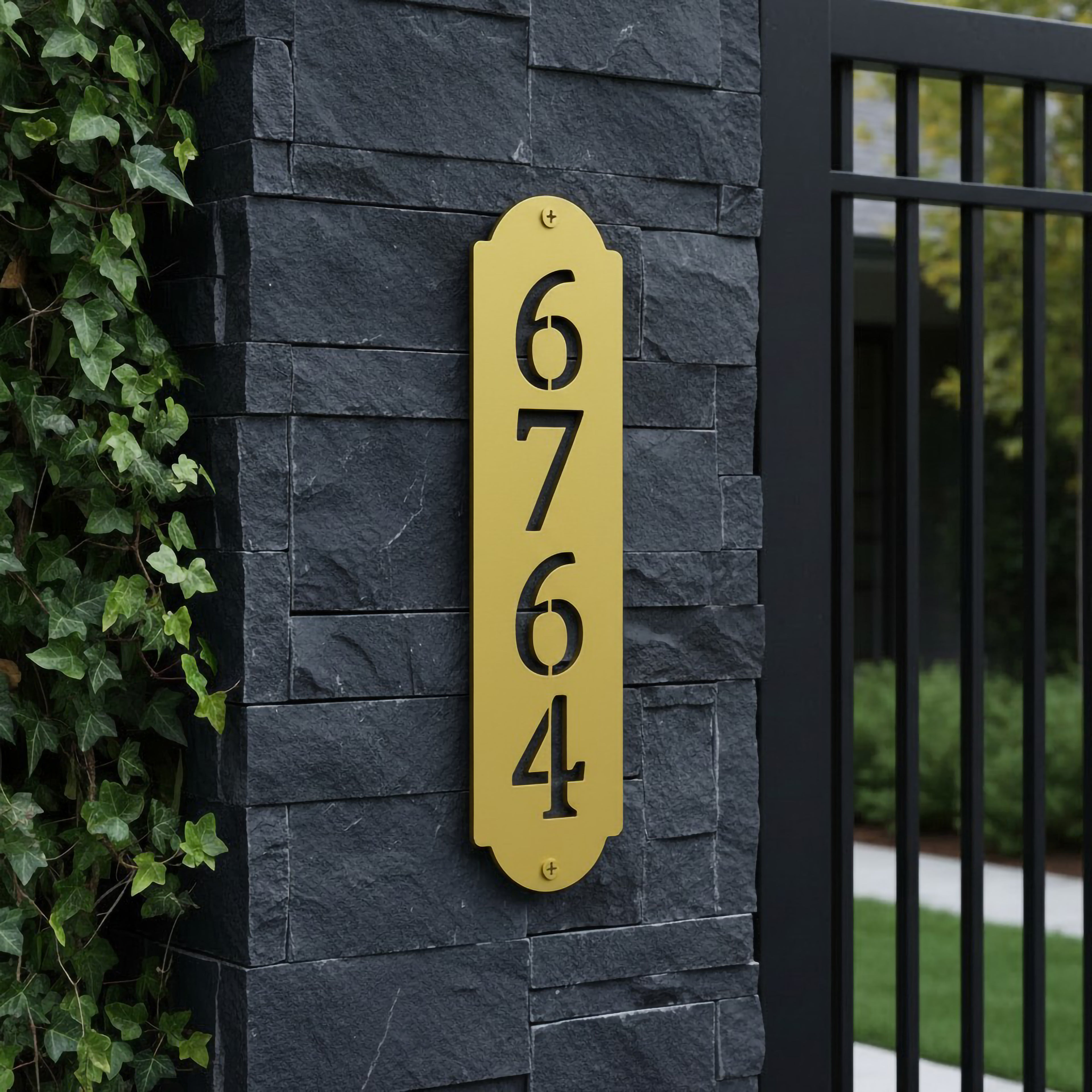 Spring yellow vertical address plaque with black cutout numbers mounted on a dark stone entrance pillar
