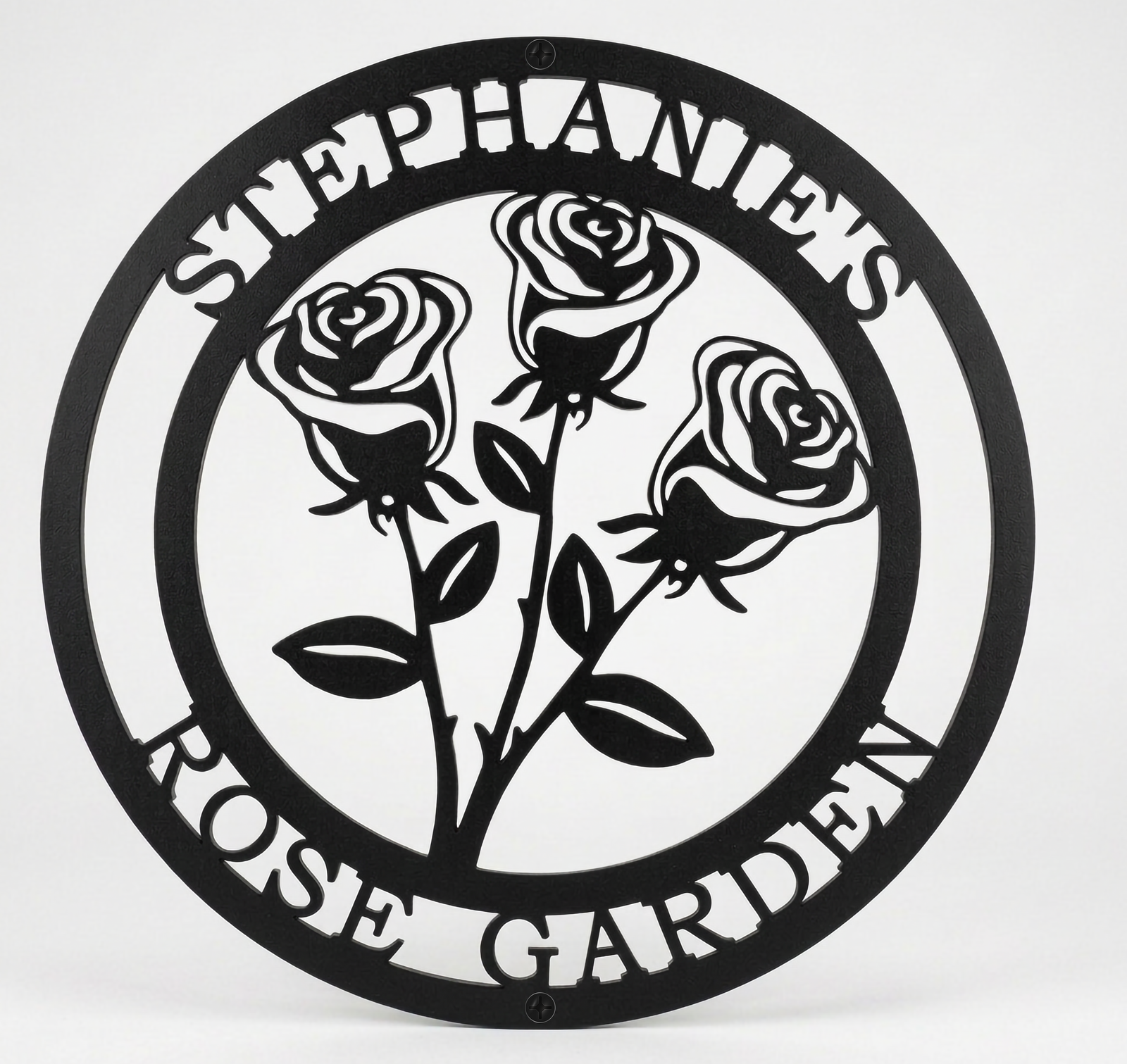 Flat view of a black circular personalized metal sign featuring a stylized three-rose bouquet cutout with the name layout over a pure white background.