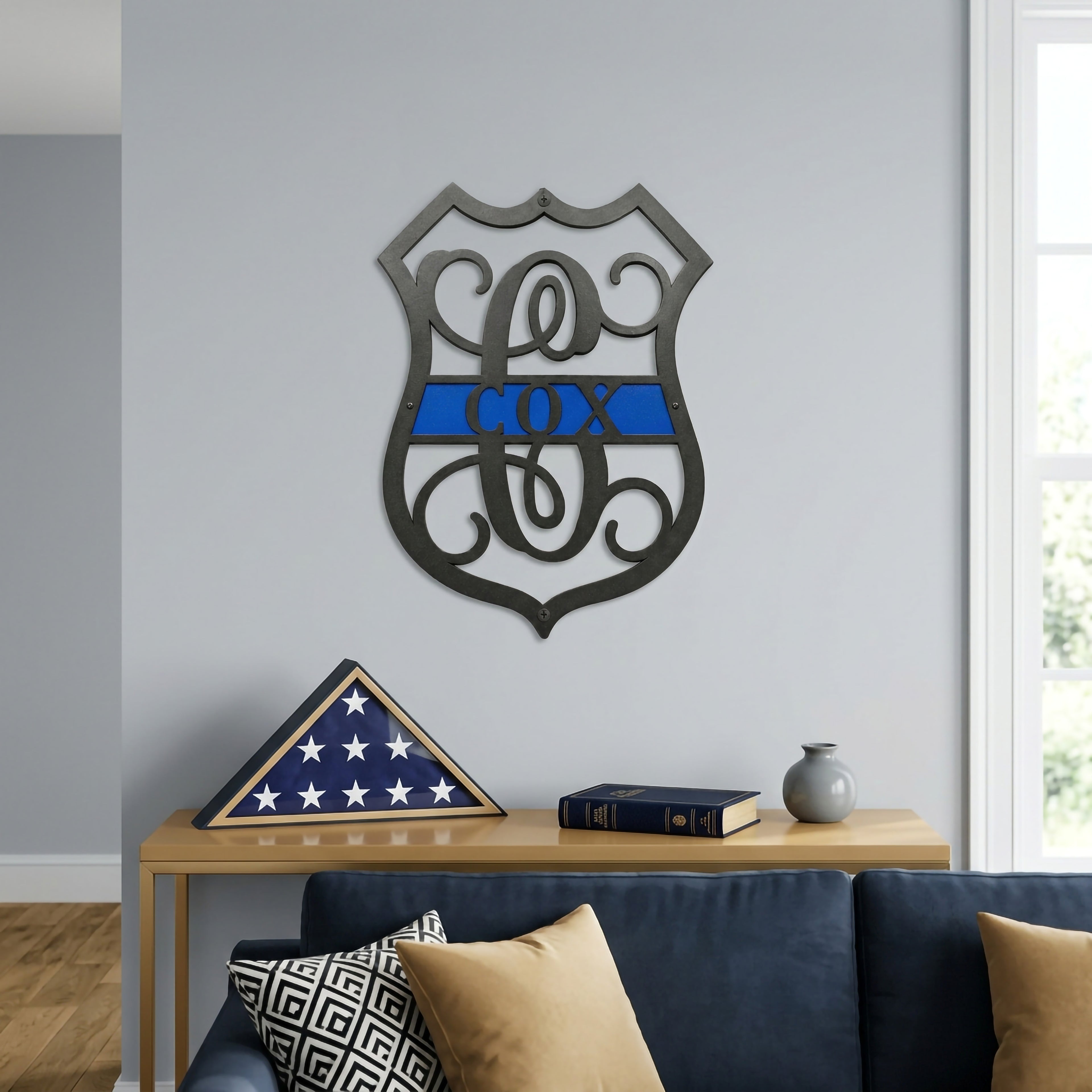 Personalized thin blue line metal monogram sign displayed above sofa with folded American flag and modern living room decor