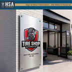 Large brushed metal tire shop automotive sign mounted outside modern garage building with custom business branding