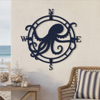 Deep navy blue finish of the custom octopus compass metal wall art displayed on an outdoor wall next to a wicker chair with a striped cushion.