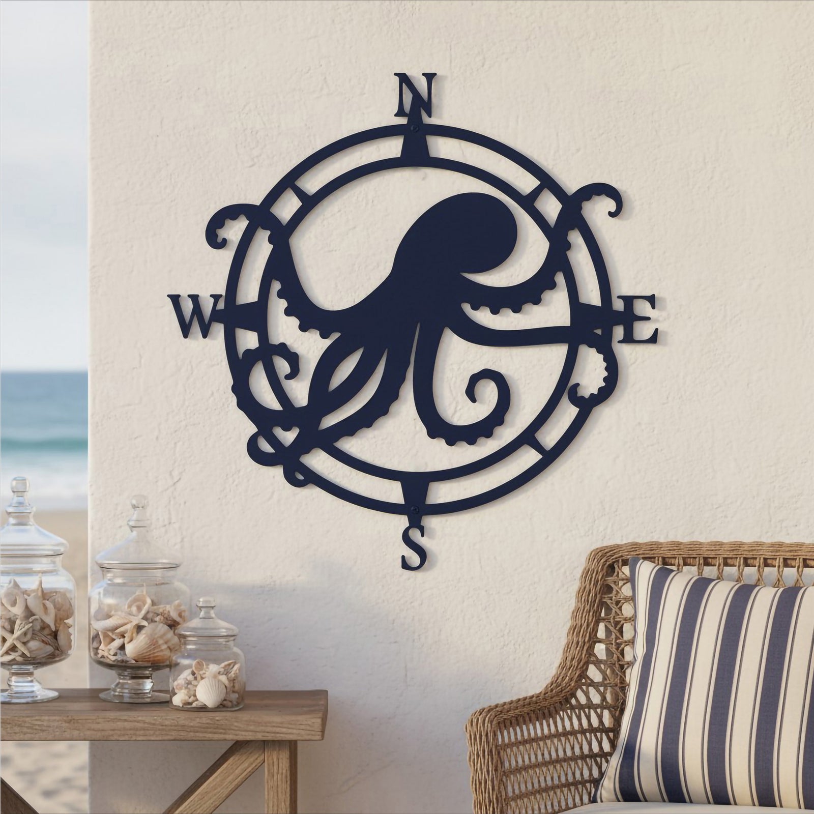 Deep navy blue finish of the custom octopus compass metal wall art displayed on an outdoor wall next to a wicker chair with a striped cushion.