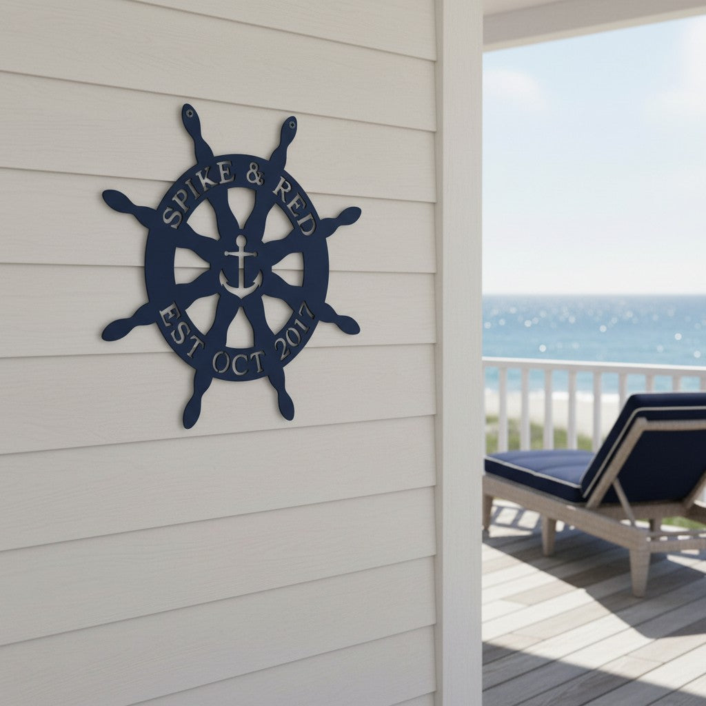 Navy blue finish of the personalized anchor ship wheel plaque mounted on an outdoor wall overlooking a sunny ocean view with a blue patio lounger.