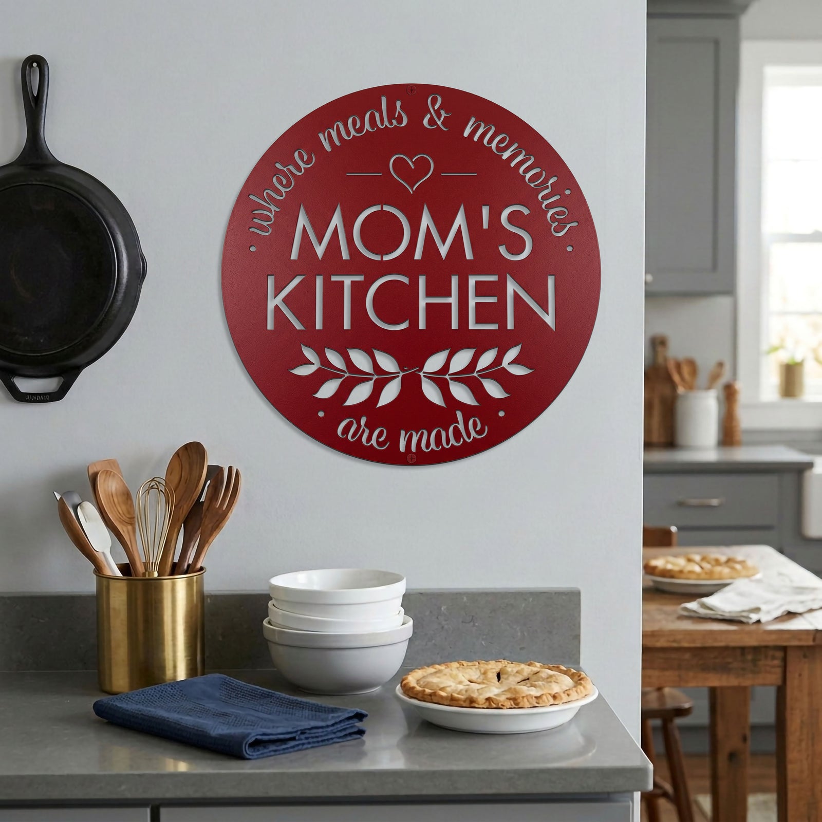 Deep red moms kitchen metal wall decor mounted in cozy kitchen beside cookware bowls and homemade pie display