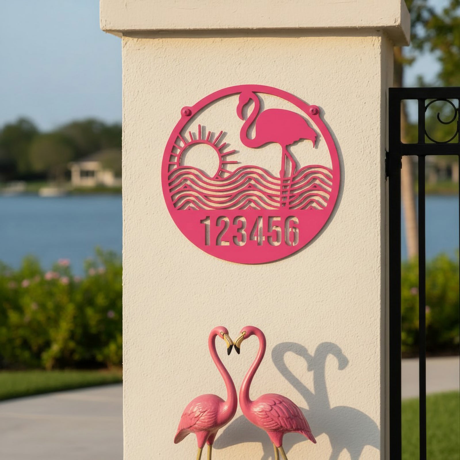 Sassy pink flamingo address sign with sunset waves and number 123456 on stucco pillar