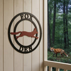 Personalized fox den metal sign with leaping fox design mounted on a porch wall beside a wooded outdoor view