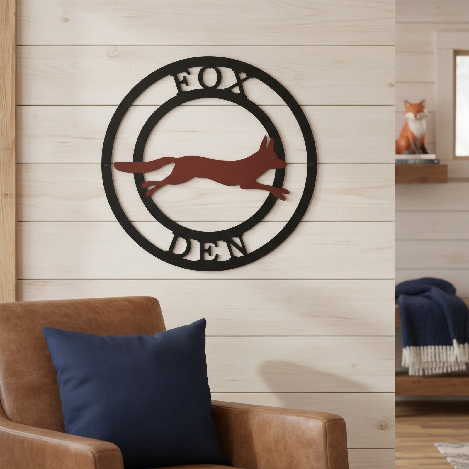 Personalized fox den metal wall sign with black round frame and rust fox design mounted on a porch wall overlooking the woods