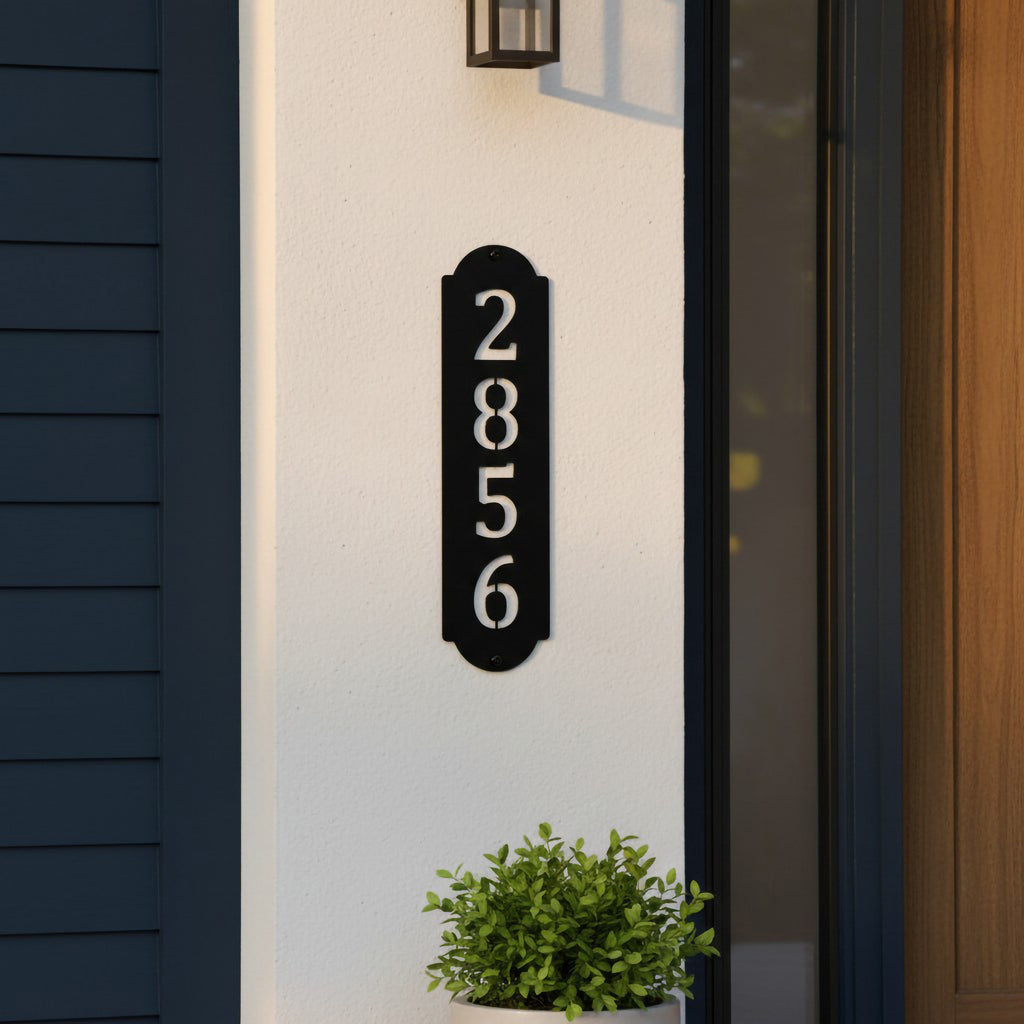 Gloss black vertical metal house number sign mounted beside a front door on a white exterior wall