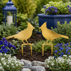 Gold cardinal metal garden stakes displayed in a flower bed with blue and white blooms for outdoor garden decor