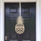 Gold pineapple welcome front door hanger shown close up on black door for tropical entryway decor