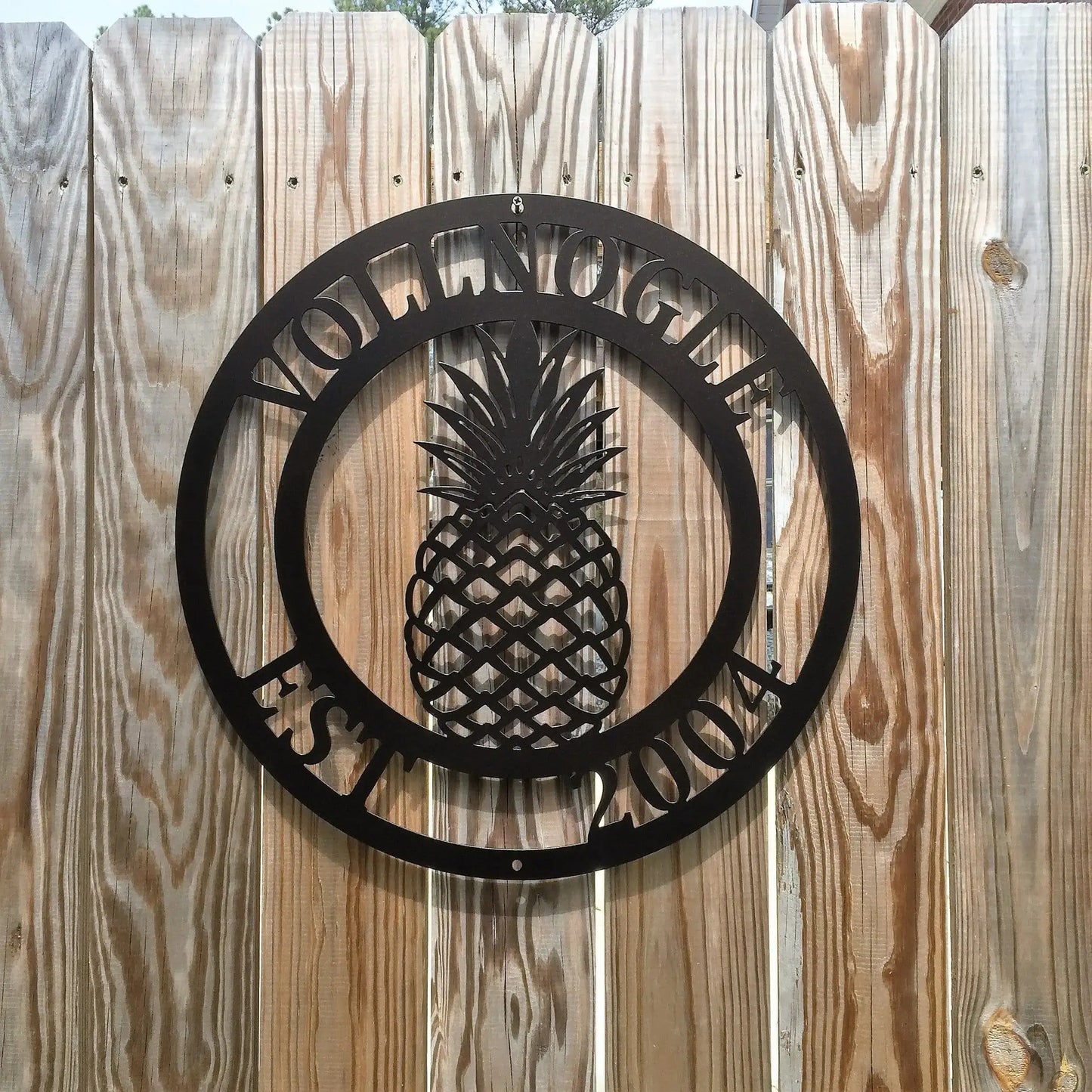 Pineapple Established Name Sign – Custom Street Numbers Sign features a black metal pineapple cutout on a wood surface, symbolizing hospitality, ideal for home décor or as a housewarming gift.