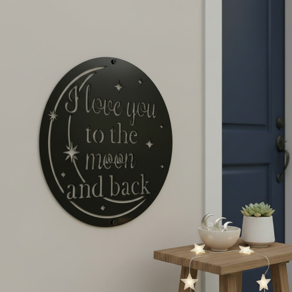 Satin black circular metal cutout sign with "I love you to the moon and back" text mounted on a plain wall next to a wooden stool decorated with star lights.