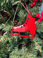Red ice skate metal Christmas ornament hanging on festive Christmas tree with pinecones and berries