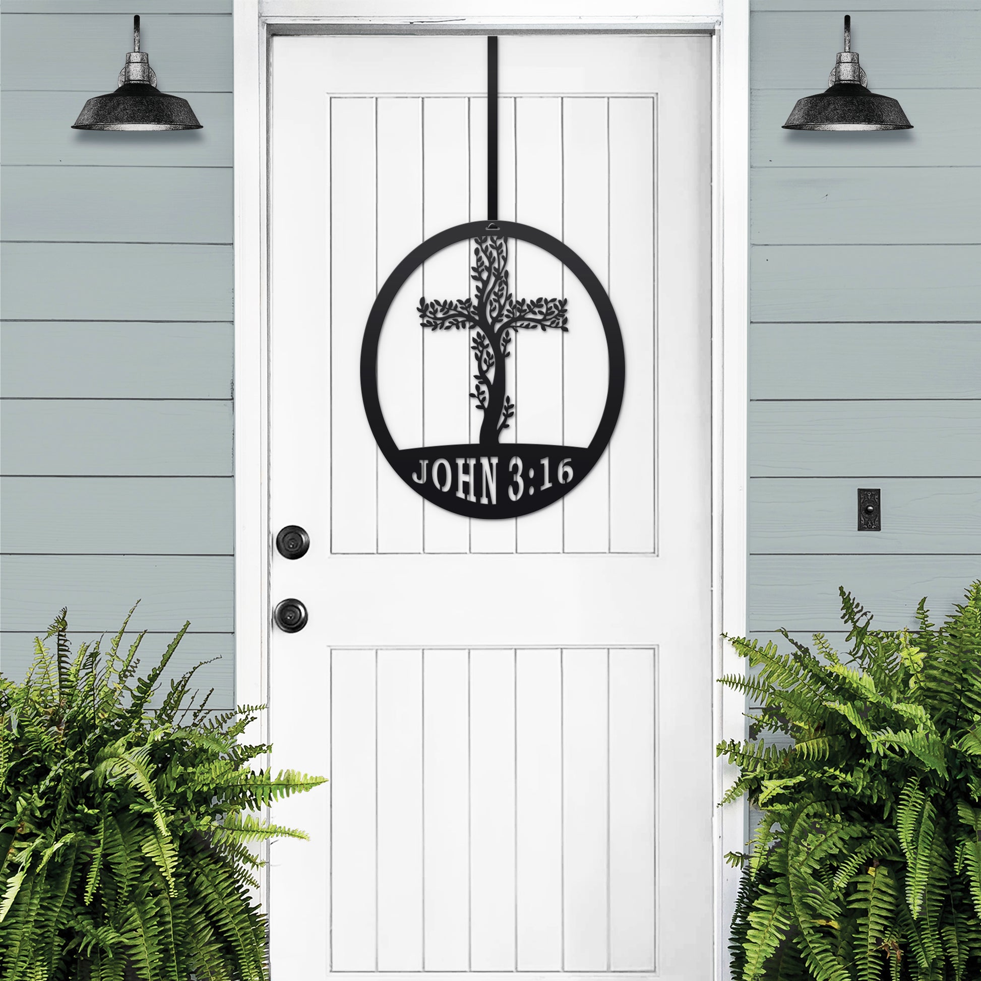 Living Tree Cross with John 3:16 Scripture Sign, featuring a black metal cross with a tree design on a white door, complemented by a nearby fern plant. Perfect for personalized Christian home decor.