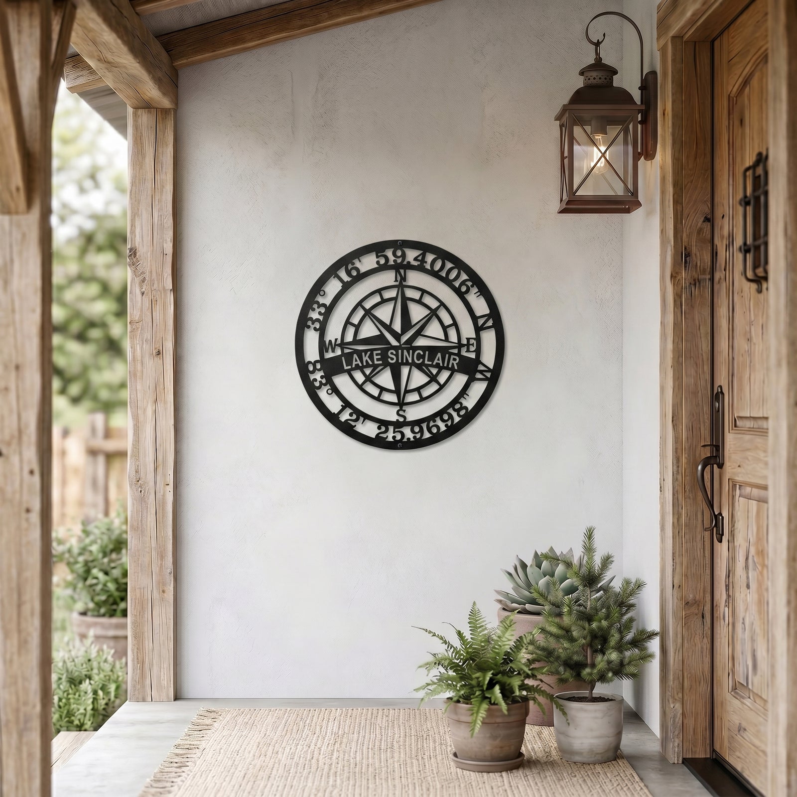 Custom Lake Sinclair compass coordinates metal sign displayed on farmhouse style porch wall with lantern and potted plants