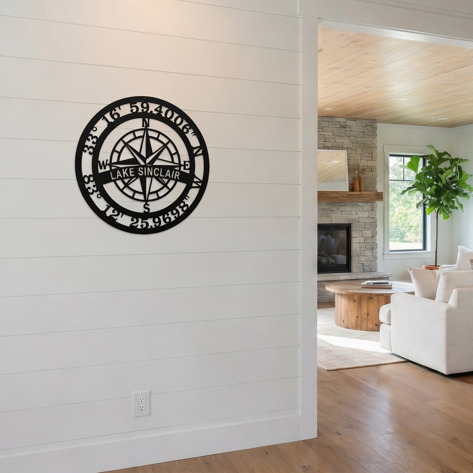Custom Lake Sinclair compass coordinates metal sign mounted on modern white shiplap wall near living room entrance