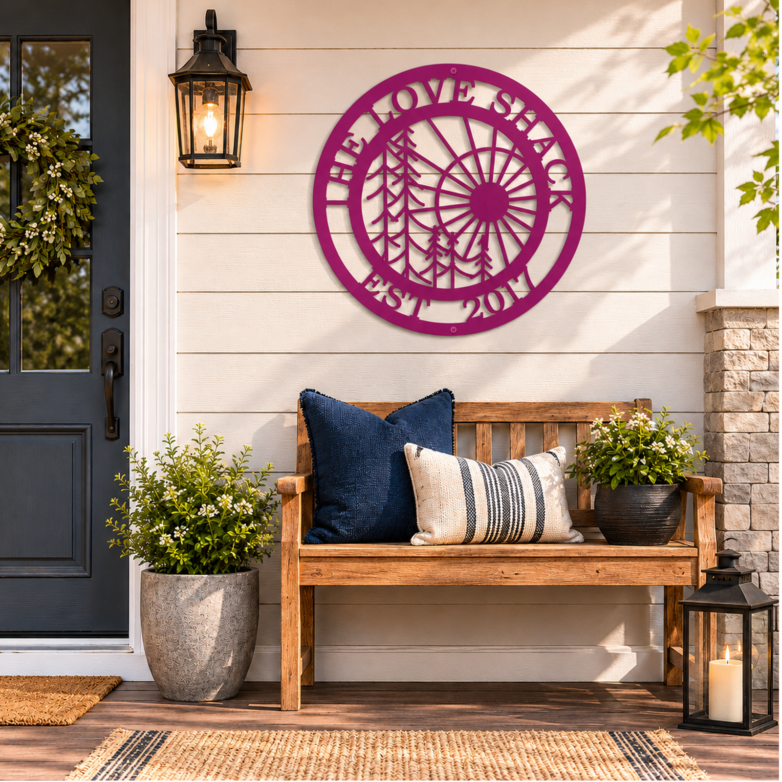 Magenta custom family name metal wall art with sun and tree design displayed above a rustic front porch bench with decorative pillows