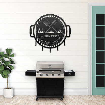 Grill Master Name Sign with Metal Hooks showcasing custom metal wall décor designed for organizing grilling utensils, featuring a black sign with a grill, fork, and spatula motif.