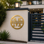 Metallic gold personalized family name monogram sign mounted on an outdoor entry wall beside a modern gate