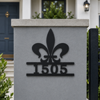 Black fleur de lis metal house number sign mounted on gray exterior wall displaying address number 1505