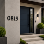 Large, modern matte black house numbers reading "0819" mounted horizontally on a light gray stucco architectural wall next to a dark blue contemporary front door with a long vertical handle.