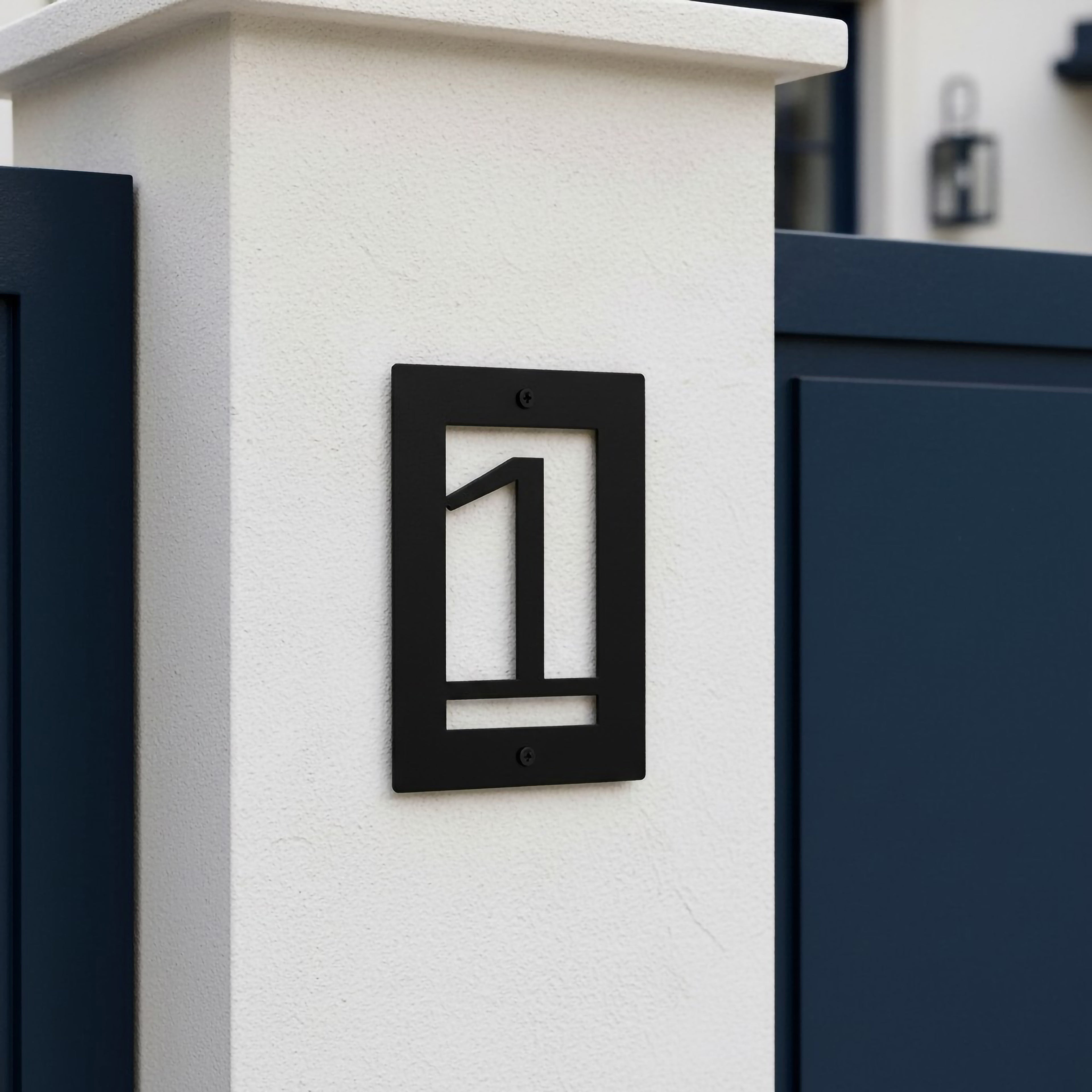 Gloss black metal house number sign 1 mounted on a white stucco pillar beside a navy gate
