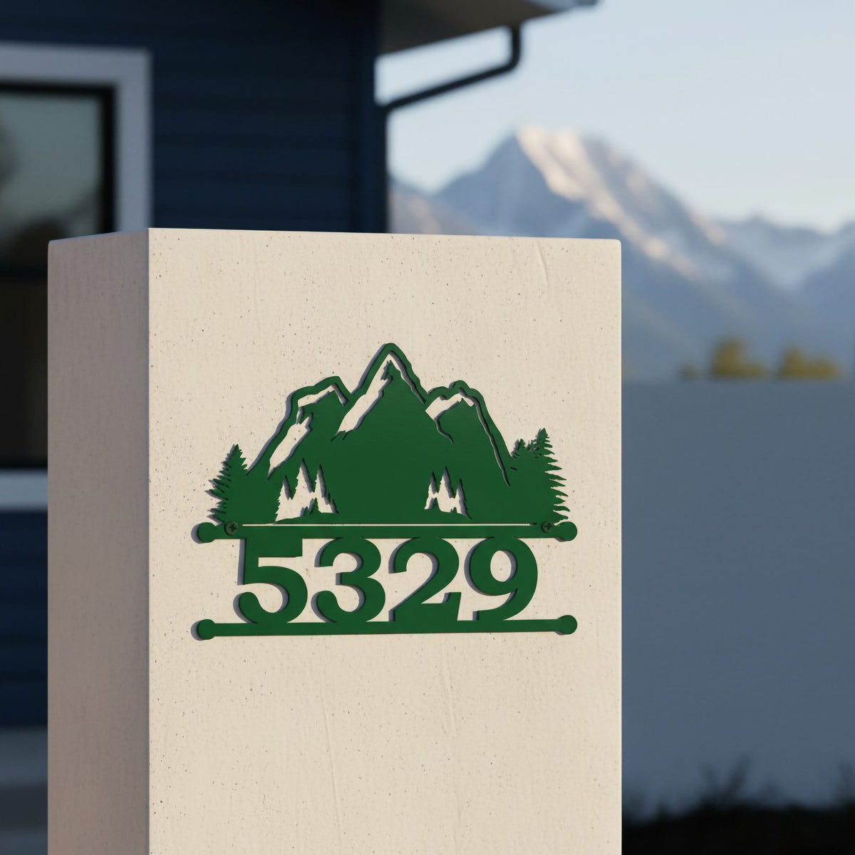 Green mountain metal house number sign with 5329 mounted on a white pillar with mountain view background