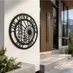 Black custom family metal wall sign with forest and sun design displayed on a modern outdoor stucco wall beside a wooden front door