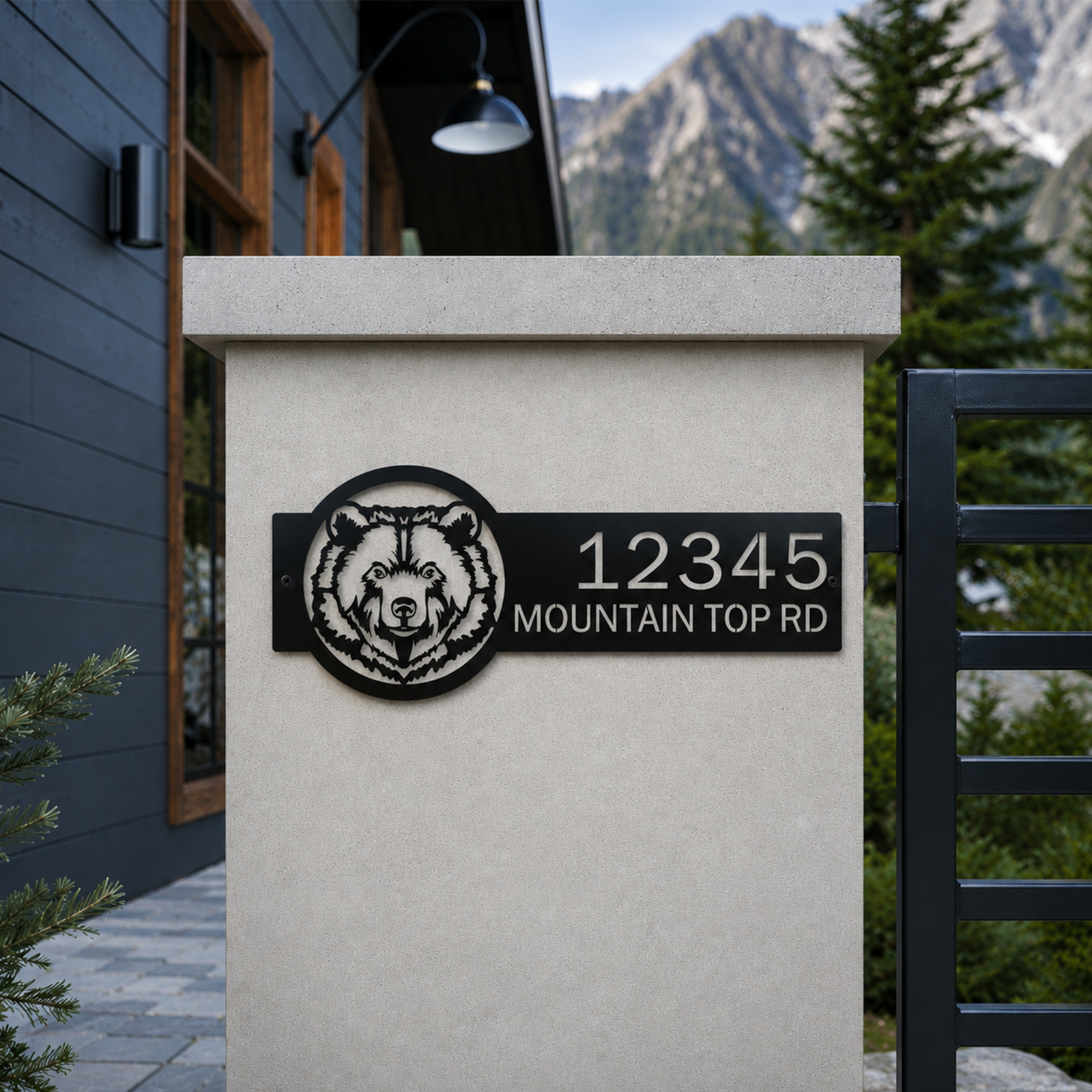 Black bear cabin address sign with custom numbers mounted on modern stone gate wall in mountain setting