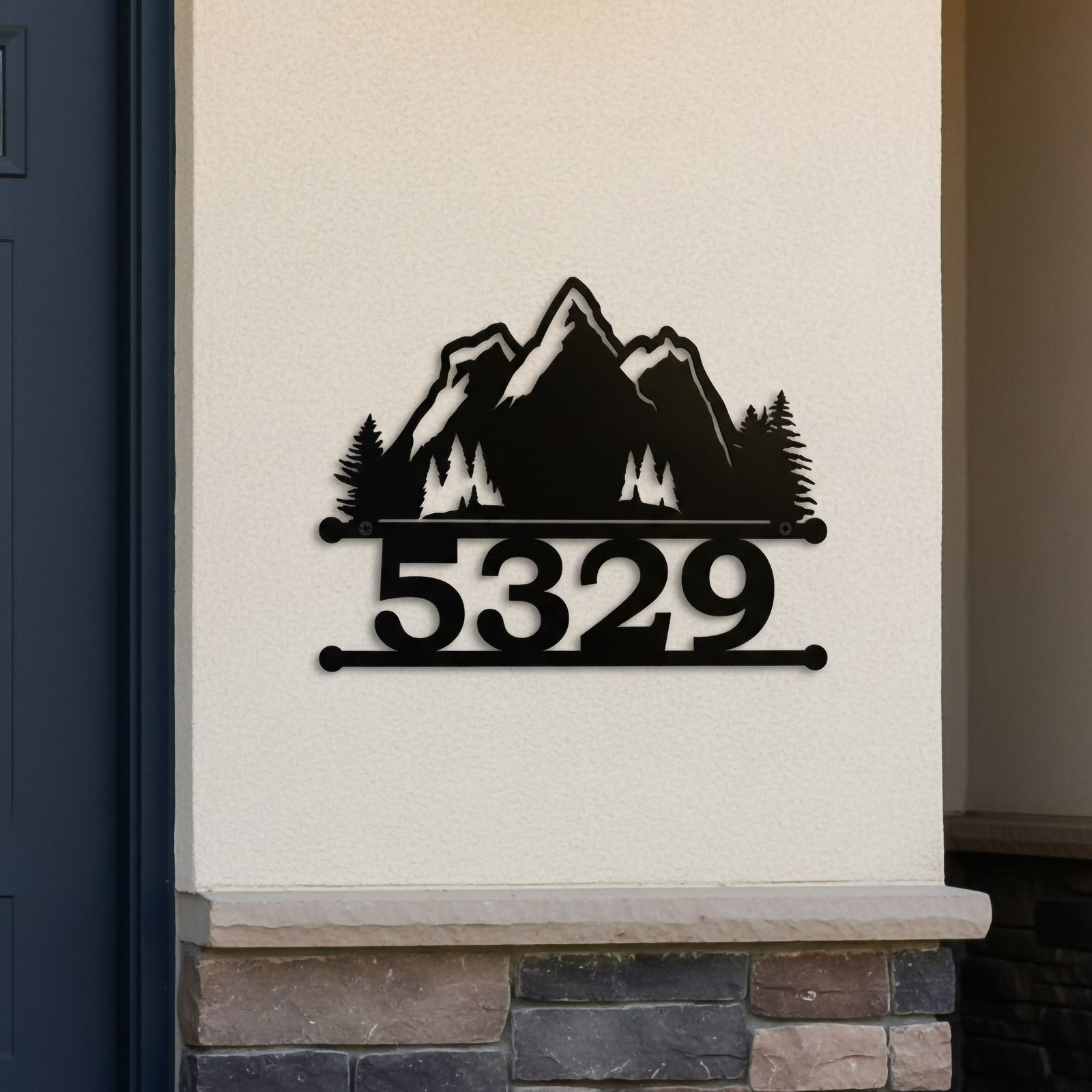 Black mountain scene metal house number sign with 5329 mounted on a white exterior wall