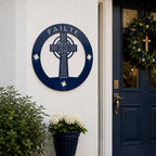 Navy blue Celtic cross metal wall art with Failte lettering displayed beside a modern front door entrance