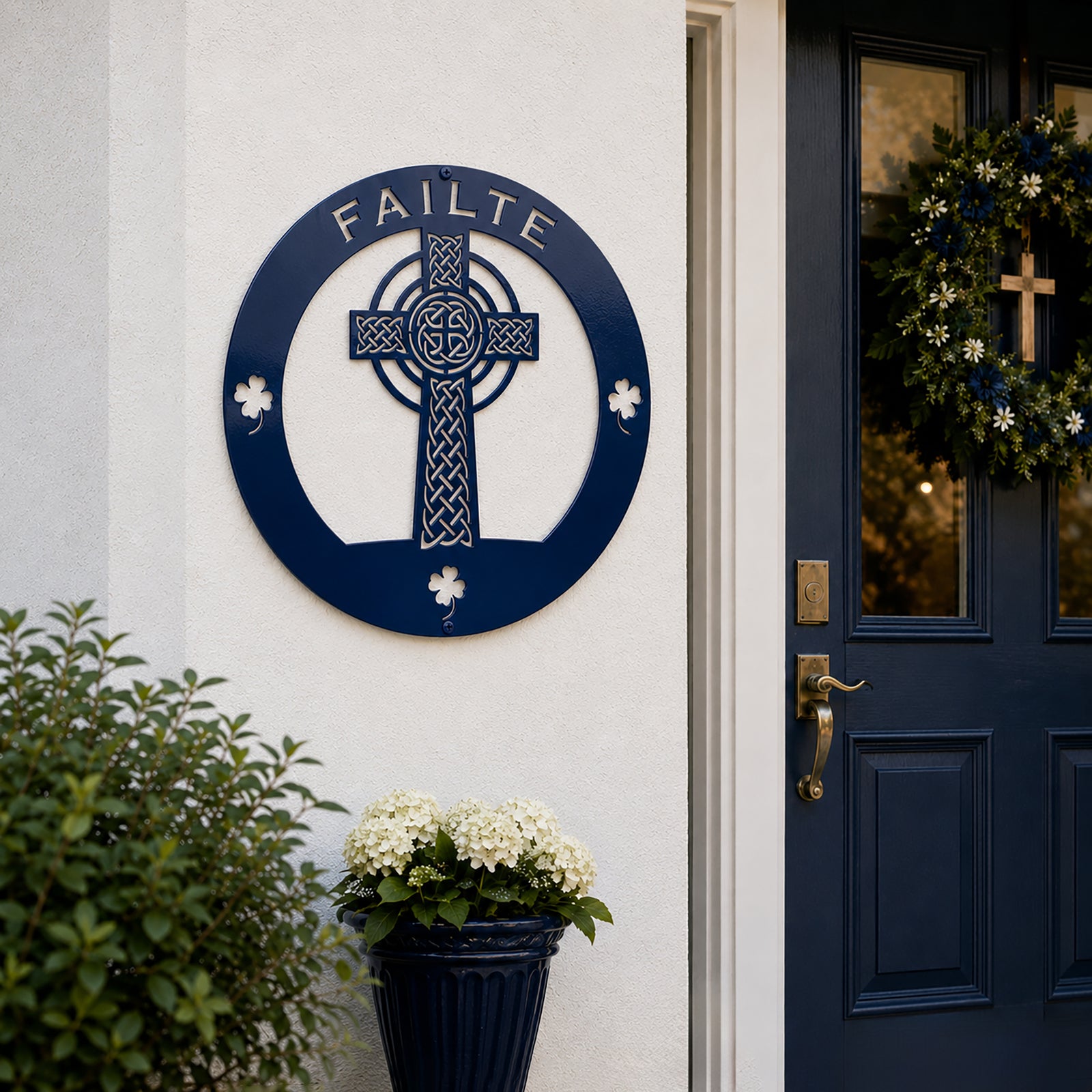 Navy blue Celtic cross metal wall art with Failte lettering displayed beside a modern front door entrance