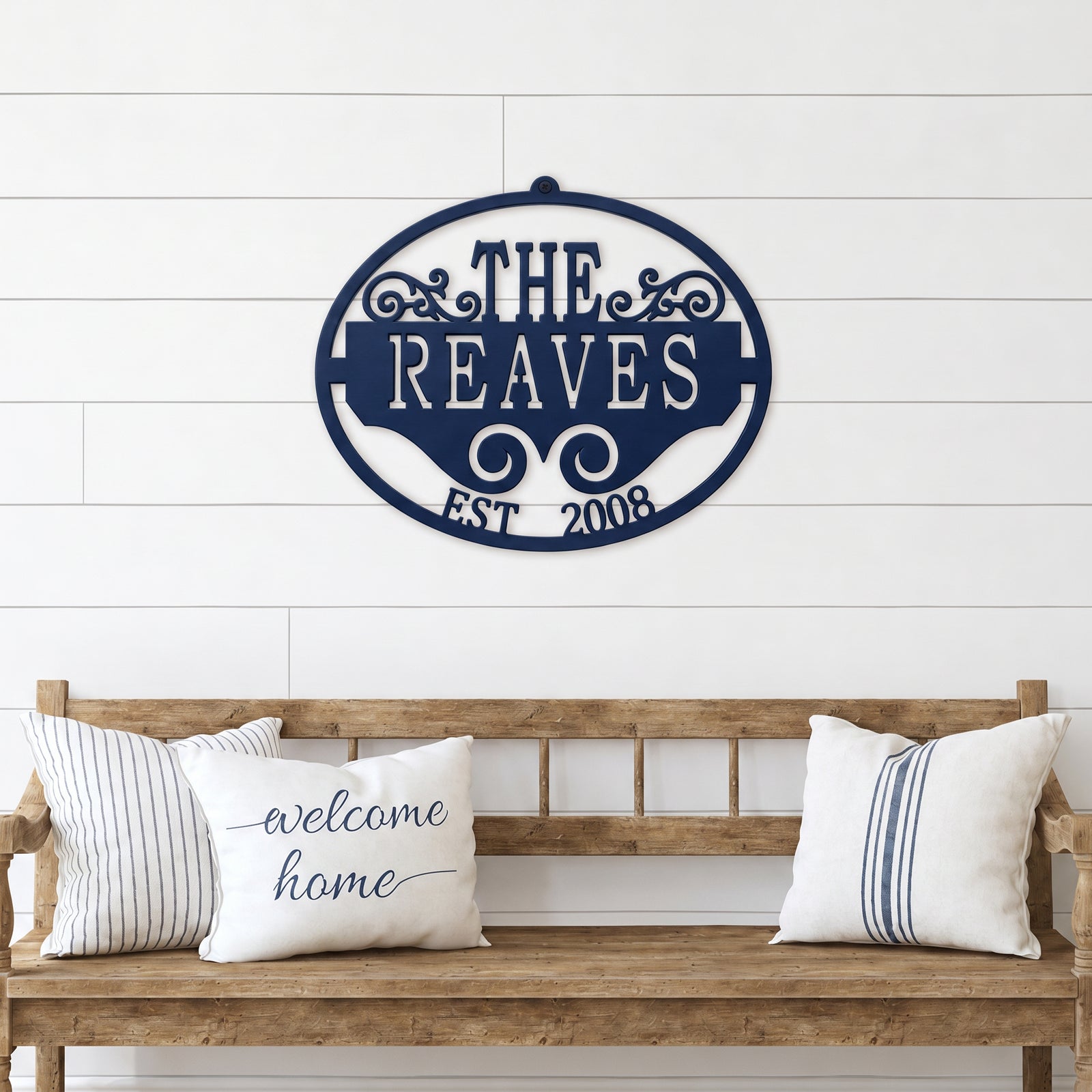Navy blue personalized family name metal wall sign with established date displayed above rustic wooden bench décor