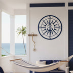 Dark navy blue finish of the custom anchor compass metal plaque mounted on a white structural wall above a striped relaxation hammock on a covered tropical veranda.