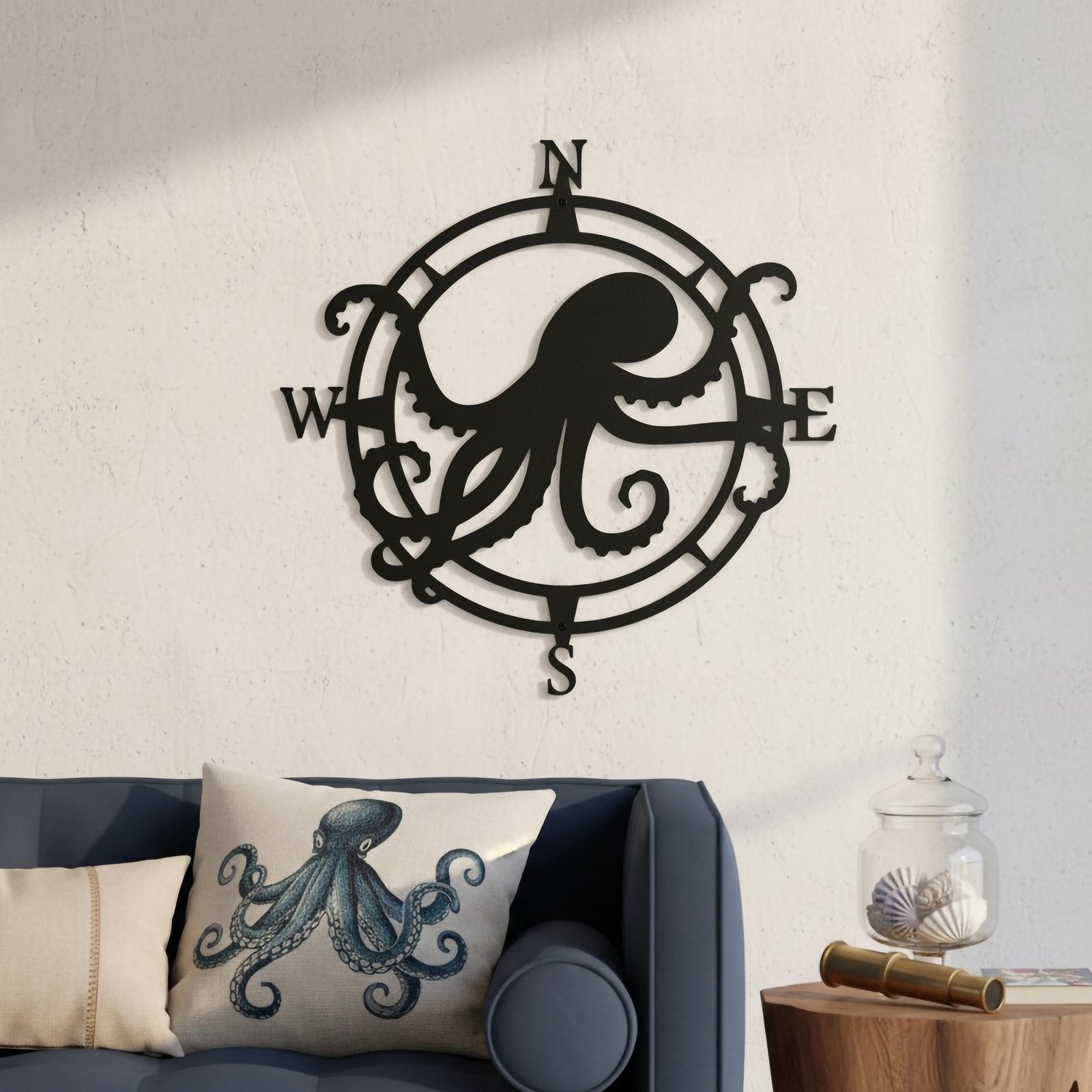 Satin black custom octopus metal compass plaque hung above a navy blue sofa with an octopus throw pillow and a brass telescope on a side table.