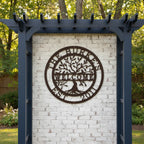A dark brown circular metal sign personalized for "The Burkes Welcome Est. 2011," displayed on a white brick structural wall beneath a navy blue garden arbor structure.