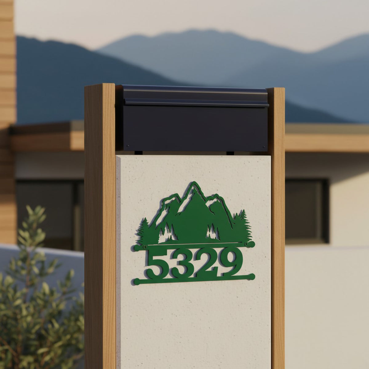 Green mountain metal house number sign with 5329 mounted on modern outdoor mailbox pillar with mountain backdrop